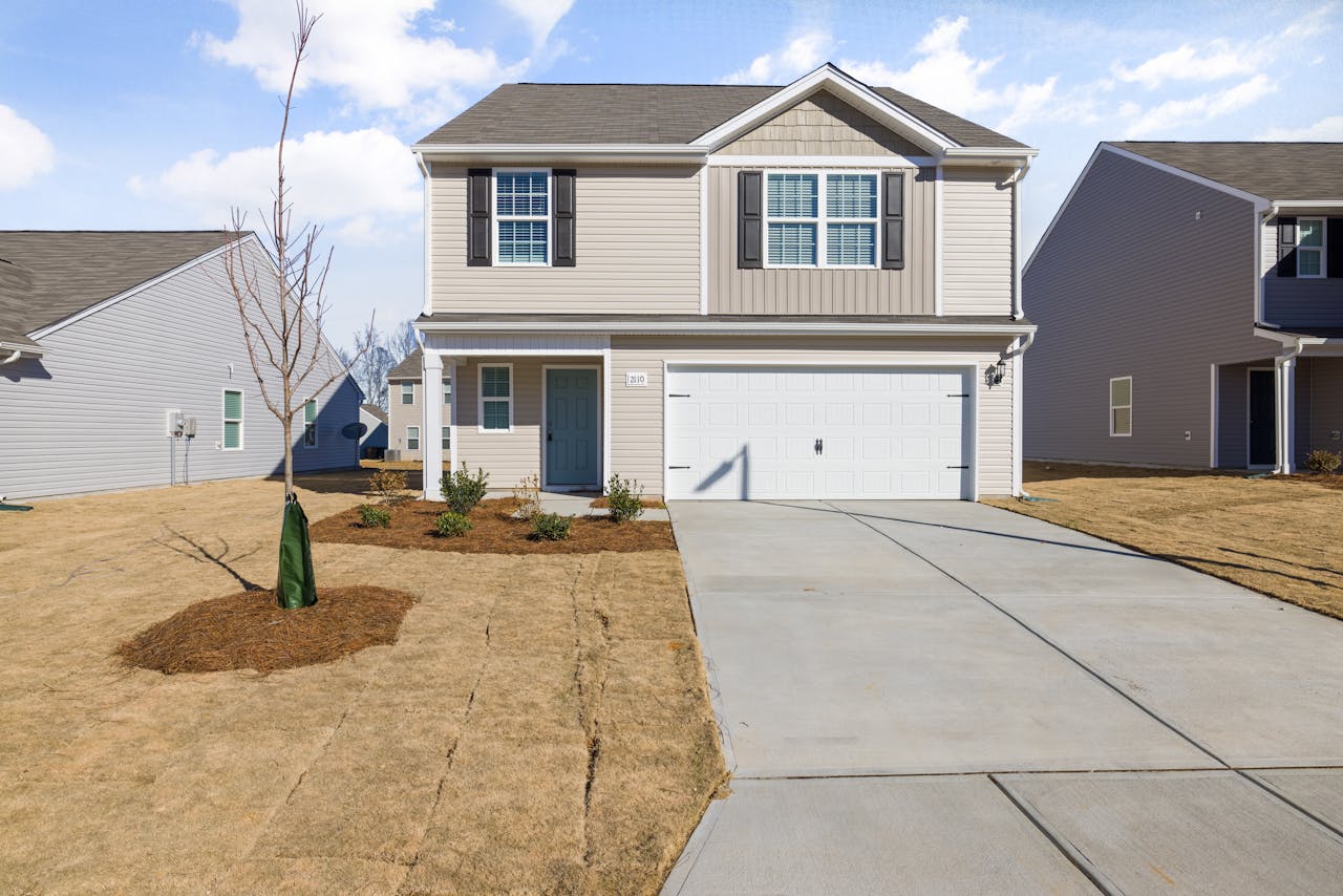 services-02 A contemporary suburban house with a spacious driveway and garage under a clear sky.