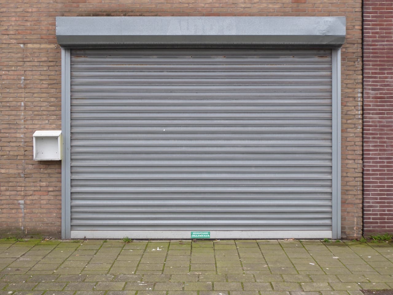 services-03 Closed grey metal roller shutter door for security and protection in urban exterior.